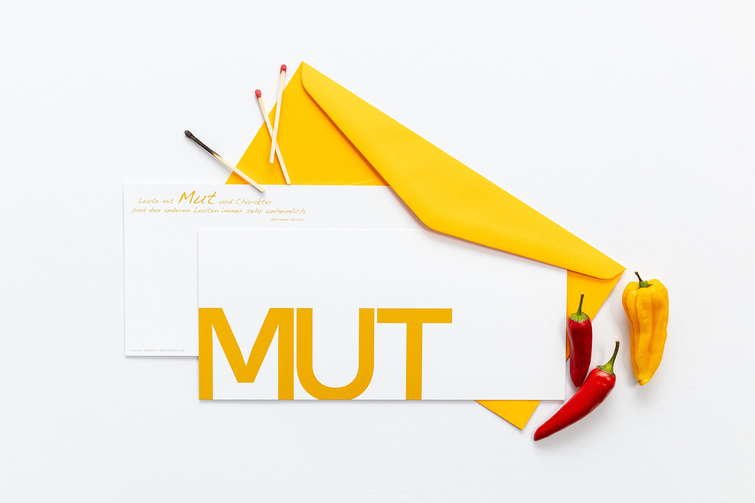 Grußkarte "MUT" mit passenden Accessoires: Streichhölzern und orangen Chillies